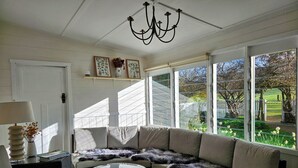 A sunlit room with a curved sofa, a round glass table, and a chandelier. - The Mia Mia Newstead - Pet Friendly Country Retreat close to town (Newstead)