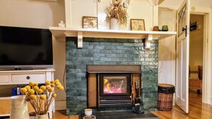 A living room with a fireplace, a television, and a glass of wine on a table. - The Mia Mia Newstead - Pet Friendly Country Retreat close to town (Newstead)