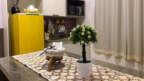 A kitchen with a yellow cabinet, a white countertop, a potted plant, and a crocheted placemat.