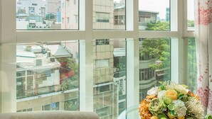 A room with a large window, a glass table with a floral arrangement, and a sofa. - Lucky Star Hotel 266 De Tham (Ho Chi Minh City)