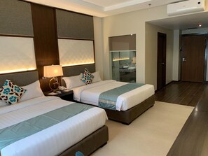 A hotel room with two beds, a bathroom with a mirror and sink, and a door leading to another room. - J7 Plaza Hotel (Iloilo)