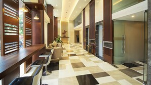 A hotel lobby with a checkered floor, seating area, and a glass-enclosed shower.