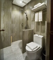 A modern bathroom with a shower, toilet, and towel rack.