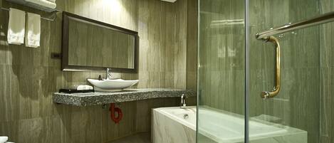 A modern bathroom with a glass-enclosed shower, a marble sink, and a toilet.