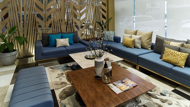 A modern living room with a blue sofa, a wooden coffee table, and hanging pendant lights.