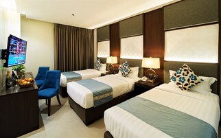 A hotel room with two beds, a desk, a chair, a TV, and a fruit basket.