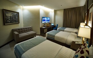 Una habitación de hotel con dos camas, un escritorio con una computadora portátil, un televisor y un sofá.