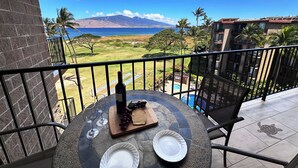 Un balcon avec une table dressée pour deux personnes, une bouteille de vin et une assiette de raisins.