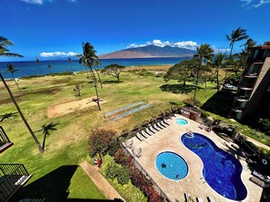 A residential area with a swimming pool, a golf course, and a view of the ocean and mountains.