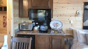 Une cuisine de taille réduite, dotée de meubles en bois, d’un four à micro-ondes, d’un grille-pain et d’un évier.