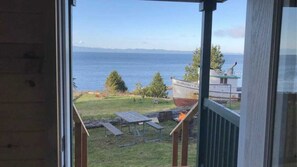 Vista dalla finestra su una zona erbosa con una barca chiamata "MARGARET B" e tavoli da picnic.