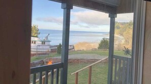 Une vue depuis une véranda donnant sur une plage, avec un foyer installé dans le jardin.