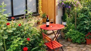 A small outdoor patio with a table and chairs, surrounded by potted plants and flowers. - Atelier d'artiste / artist loft / 35m2 (Paris)