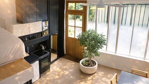 A compact kitchen with a stove, cabinets, and a potted plant. - Atelier d'artiste / artist loft / 35m2 (Paris)
