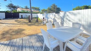 A wooden deck with white plastic chairs and a table, surrounded by a white fence and trees. - Charming Renovated House with Garden, 300m from Beach, WiFi Included (Bretignolles-sur-Mer)
