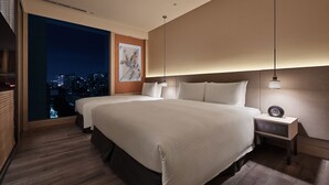 Una camera d'albergo moderna con un letto grande, un comodino e vista sulla città attraverso un'ampia finestra.