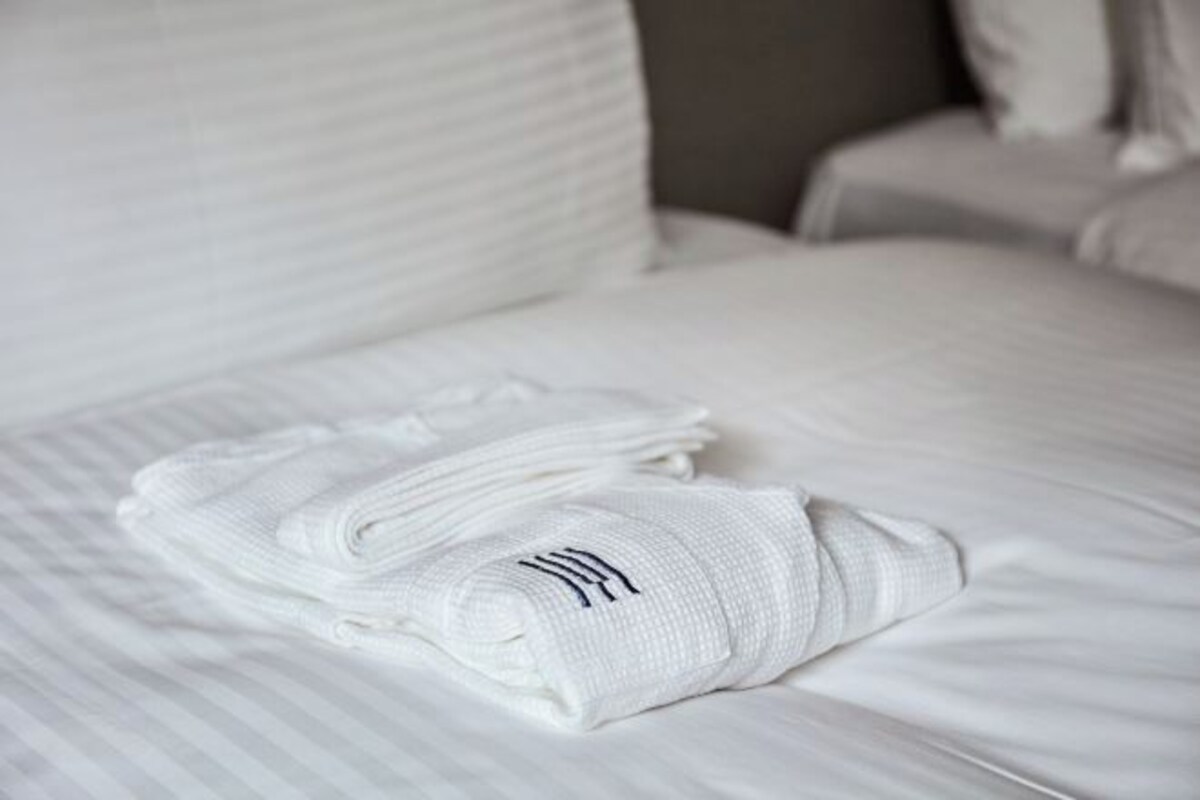 A neatly made bed with white bedding and folded towels.