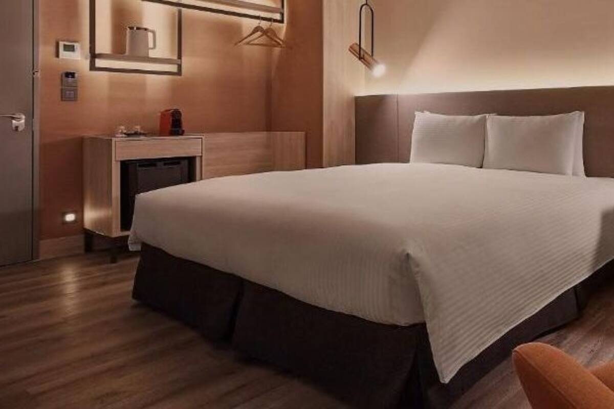 A hotel room with a large bed, a desk, and a chair.