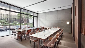 Une salle de conférence dotée d’une longue table, de chaises et d’un mur en verre donnant sur l’extérieur.