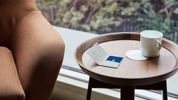 Un sillón de cuero marrón junto a una mesita de madera con una taza blanca y un menú.