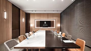 Una sala de conferencias moderna con una larga mesa, sillas cómodas y una pantalla grande que muestra el logotipo.