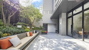 Un'area esterna moderna con sedute, un fioriere con fiori e un muro di vetro che si affaccia sull'interno.