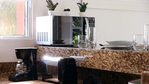A kitchen with granite countertops, a microwave, a coffee maker, and a painting on the wall. - "Experience the Caribbean Lifestyle at Suites Lorens" (Isla Mujeres)