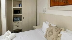 A hotel room with a bed, a wardrobe, a nightstand, a wall-mounted lamp, and a painting of a boat. - "Experience the Caribbean Lifestyle at Suites Lorens" (Isla Mujeres)
