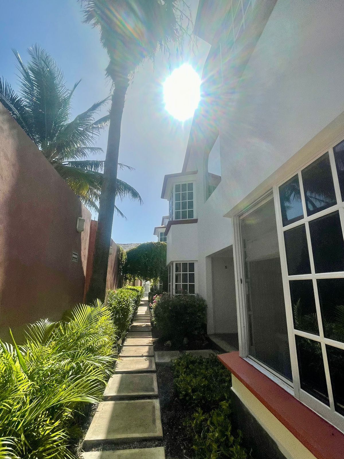 A pathway leading to a white building with a large window and a garage door.