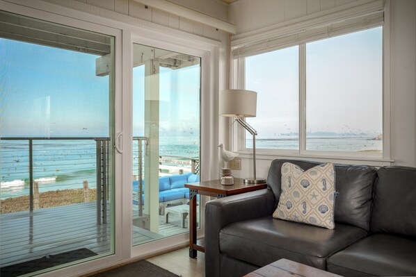 Una sala de estar con vista a la playa y al océano, un sofá, una lámpara y una mesa.