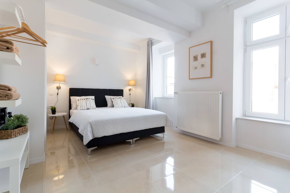Une chambre moderne avec un grand lit, des lampes de chevet, un radiateur et une fenêtre donnant sur un beau paysage.
