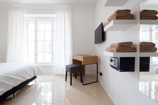 A hotel room with a bed, a desk, a chair, a TV, and a wall-mounted safe. - B&B Downtown Zagreb (Zagreb)