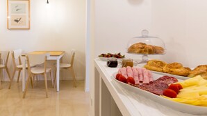 A breakfast buffet with various foods, a dining area with white chairs and tables, and framed pictures on the wall. - B&B Downtown Zagreb (Zagreb)