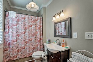 A bathroom with a patterned shower curtain, a sink with toiletries, and a mirror above the sink. - Spacious Mount Pleasant Home: 5 Mi to Beach (Mount Pleasant)