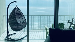 Un balcon avec un fauteuil en osier, une chaise verte et une balustrade blanche.