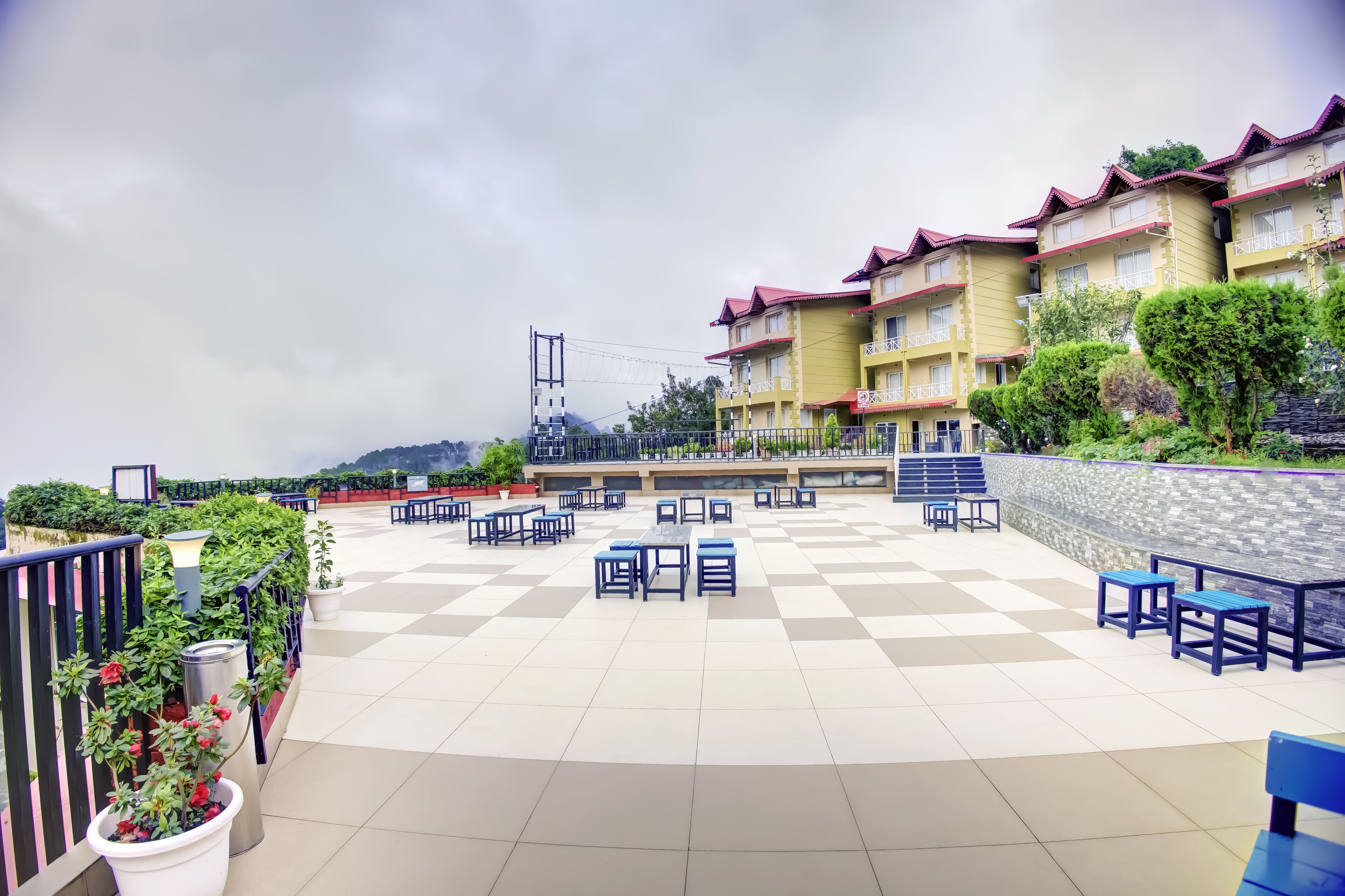 A hotel courtyard with outdoor seating, a checkered floor, and a view of a mountain.