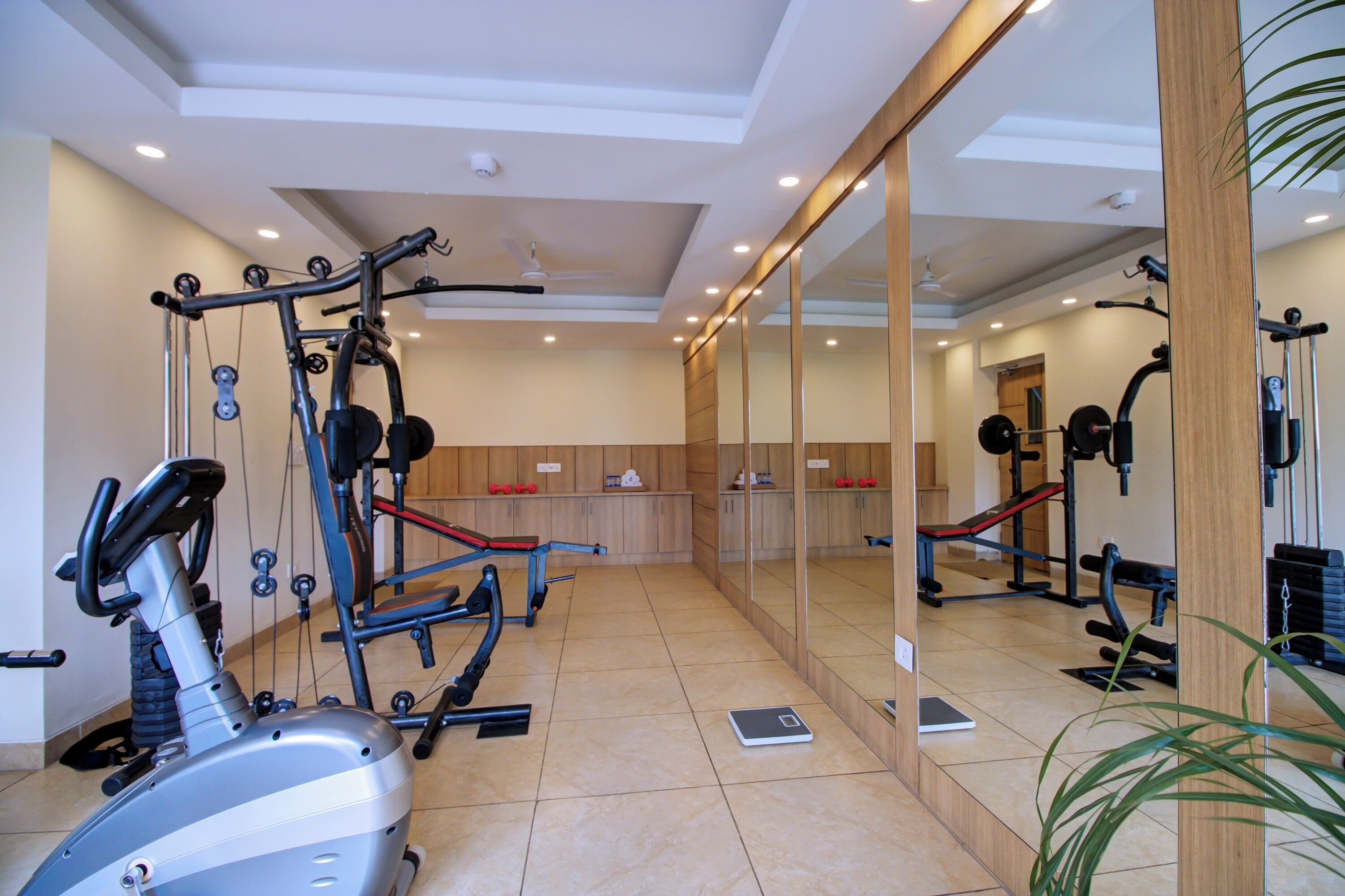 Un gimnasio con equipo de ejercicio, un espejo grande y una balanza en el suelo.