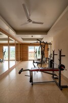 A gym with exercise equipment, large windows, and a ceiling fan.