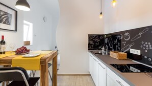A modern kitchen with a wooden table, yellow tablecloth, and a black backsplash with kitchen drawings. - Downtown Zagreb Apartments (Zagreb)