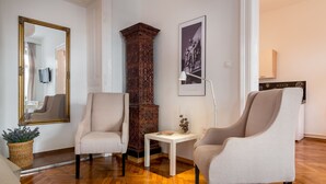 A room with two armchairs, a wooden column, a white table, and a framed picture on the wall. - Downtown Zagreb Apartments (Zagreb)