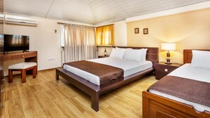 A hotel room with a large bed, a desk with a chair, a television, and a bedside table with a lamp. - Amfion Hotel (Katerini)