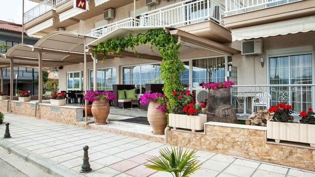 A hotel with outdoor seating, potted plants, and a covered patio area. - Amfion Hotel (Katerini)