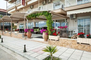 A hotel with outdoor seating, potted plants, and a covered patio area.