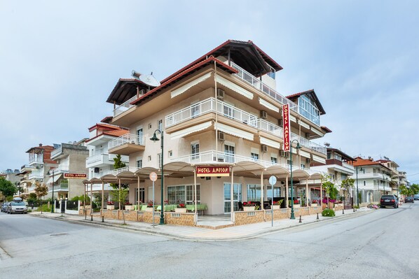 A multi-story hotel with a prominent balcony, outdoor seating area, and a sign reading "HOTEL AMFIAN".