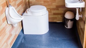 A small bathroom with a wooden floor, a white toilet, a sink, and a urinal.
