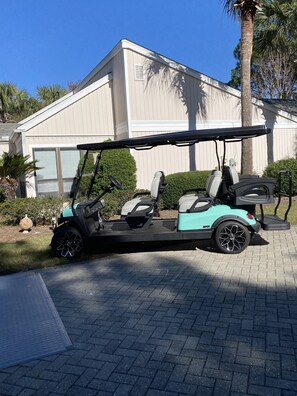 Een golfkarretje geparkeerd voor een huis met een garage.