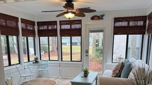 A sunroom with large windows, a ceiling fan, a white sofa, and a small table with a plant. - Beautiful One-Story Cottage Just Minutes From White Sand Beach, with Golf Cart!  (Destin)