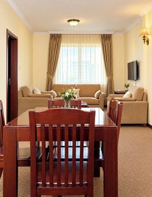 A hotel room with a dining table, chairs, a sofa, and a television. - Debredamo Hotel (Addis Ababa)