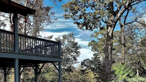 A wooden deck with railings overlooking a lake, surrounded by trees and greenery.