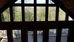 A room with large windows offering views of a deck and surrounding trees.